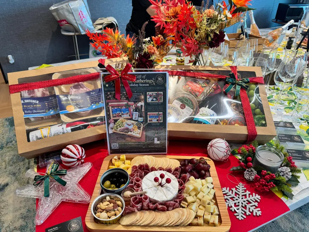 Holiday gift boxes behind a charcuterie board with brie, salami, cheese cubes, olives, nuts and crackers