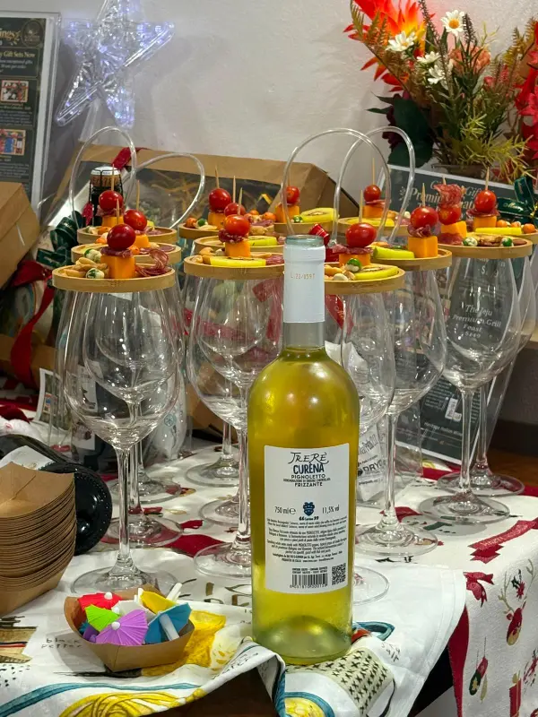 Wine glasses topped with small plates of tomato, cheese and salami bites, with a bottle of sparkling white wine